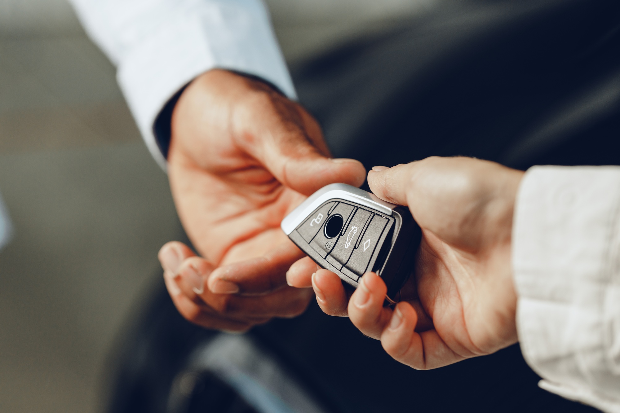 Car salesperson giving keys to a client close up
