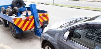 Tow truck towing a broken down car on the street