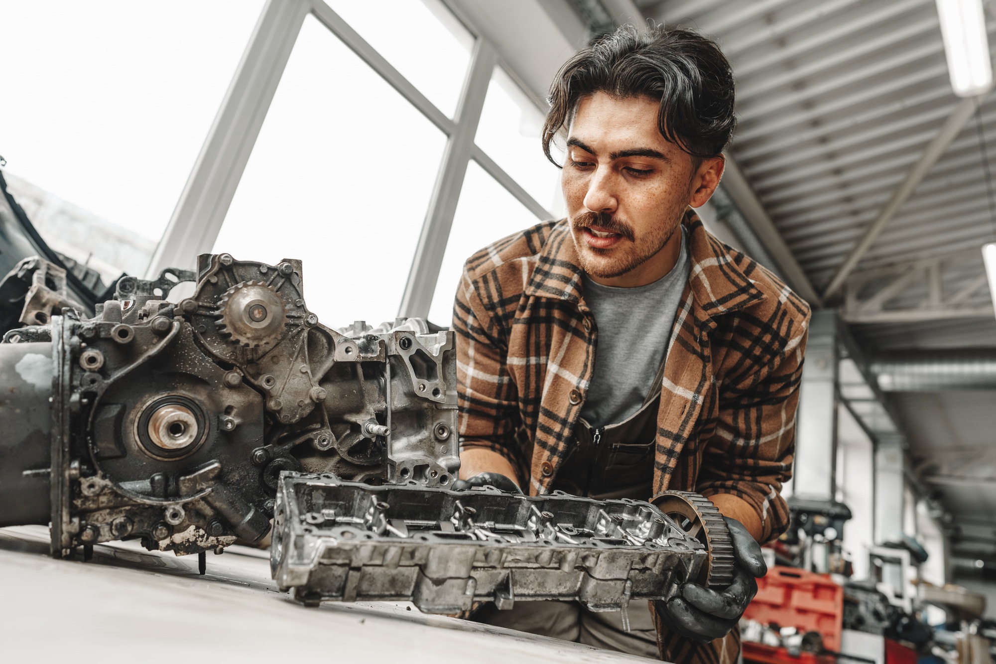 Workman disassembling car engine at the working table of the car service garage